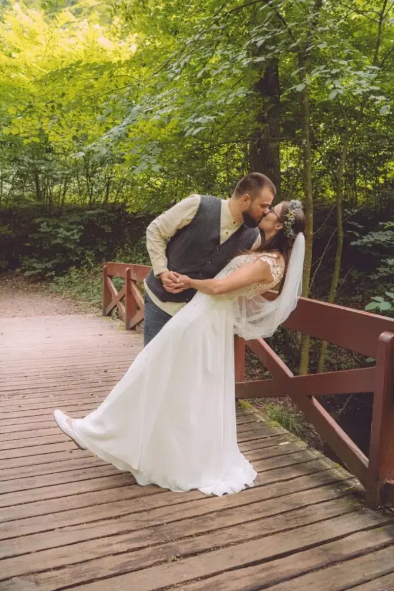 Groom dipping the bride for a kiss on a wooden bridge